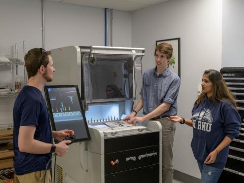 学生 standing around makerspace equipment